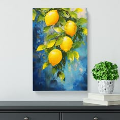 a painting of lemons hanging on a wall next to a potted green plant