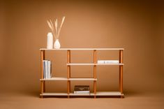 a shelf with books, vases and other items on it in front of a brown background