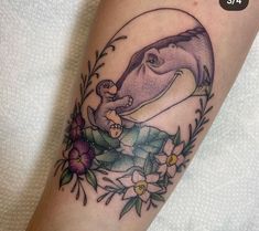 an elephant and bird tattoo on the left arm, with flowers around its ankles in front of it