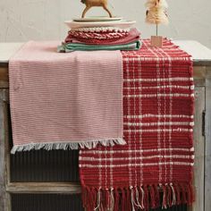 a red and white checkered blanket on top of a wooden cabinet next to a small deer figurine