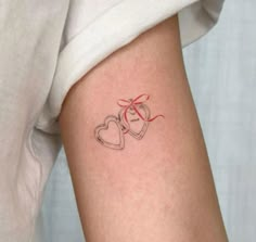 a woman's arm with two hearts and a bow tattoo on her left side