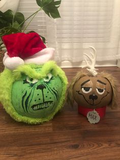 two stuffed animals wearing christmas hats on top of a wooden floor next to a potted plant