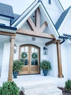 a white house with two potted plants on the front porch and an entryway