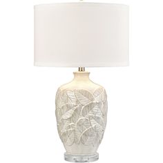 a table lamp with a white shade on the base and leaves printed on the bottom