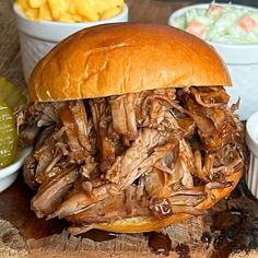 a pulled pork sandwich sitting on top of a wooden cutting board