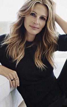 a woman sitting on top of a couch next to a white wall with her hand on her head