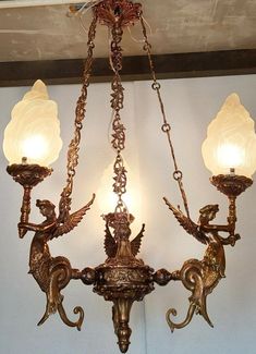 an ornate chandelier with three lights hanging from it's sides and two cherubs on each arm