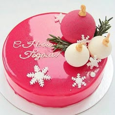 a pink cake decorated with white snowflakes and baubles is on a plate