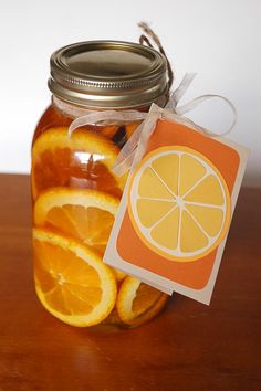 a jar filled with sliced oranges sitting on top of a wooden table next to a tag