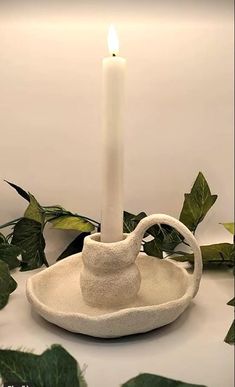 a white candle sitting on top of a bowl