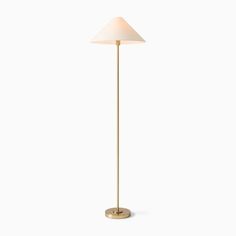 a gold floor lamp with a white shade on the base and a light bulb in the middle