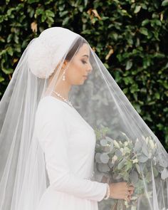 a woman wearing a veil and holding flowers