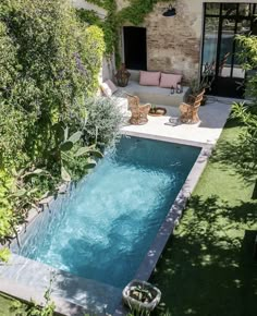 an outdoor swimming pool surrounded by greenery and furniture in a backyard area with patio furniture