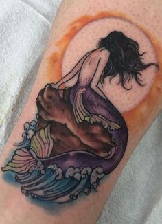 a woman sitting on top of a wave tattoo