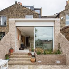 a brick house with large windows and steps leading up to the front door that lead into the back yard