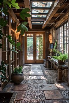 the inside of a house with lots of windows and plants in pots on the floor