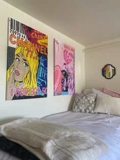 two paintings hang on the wall above a bed