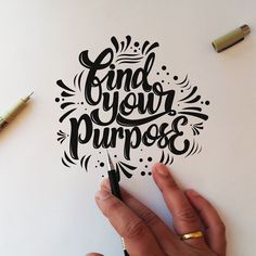 a hand holding a pen over a piece of paper with the words find your purpose on it