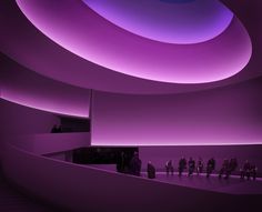 people are standing in the middle of a large room with purple lighting on the ceiling