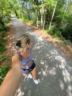 a woman is taking a selfie in the middle of a road with trees on both sides