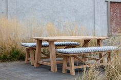 two wooden benches sitting next to each other near tall grass