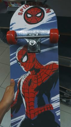 a skateboard with spiderman on it is being held by someone's hand