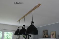 three black lights hanging from the ceiling in a room with white walls and wood beams