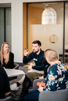 a group of people sitting around each other in a room with glass walls and doors