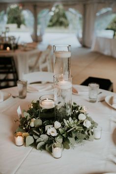 the centerpiece is surrounded by candles and greenery