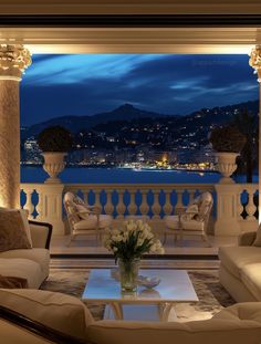 a living room filled with furniture and a view of the ocean at night in the distance