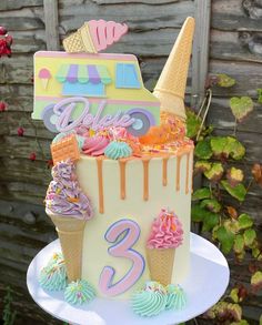 a birthday cake with ice cream and cupcakes on the top is decorated in pastel colors