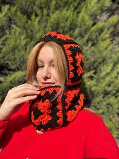 a woman wearing a red and black crocheted scarf