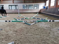 a horse and rider in an indoor arena with several poles on the ground as well