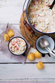 a bowl of soup with shrimp and bread on the side