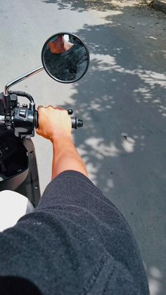 a man riding a motorcycle down a street next to a tree