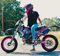 a woman in black shirt and jeans sitting on pink dirt bike