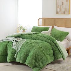 a bed covered in green fluffy blankets and pillows