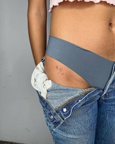 a woman's stomach with her belly exposed and the bottom part of her jeans ripped off