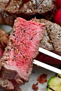 steak and vegetables on a plate with tongs