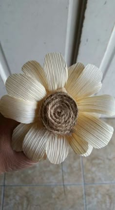 a person is holding a flower made out of folded book pages in their left hand