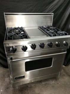 a stainless steel stove with four burners and two oven doors on the front side