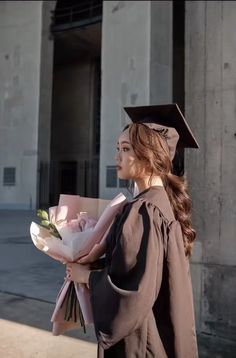 a woman in a graduation gown holding flowers