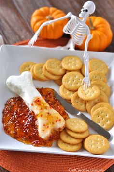 a white plate topped with crackers and sauce next to a skeleton on a table