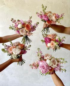 four bridesmaids holding bouquets of pink and white flowers in their hands against a wall