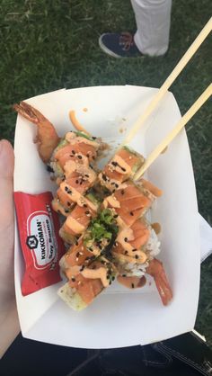 a person holding a plate with food on it and chopsticks in their hand