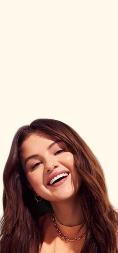 a woman with long brown hair smiling and wearing a gold chain necklace on her neck