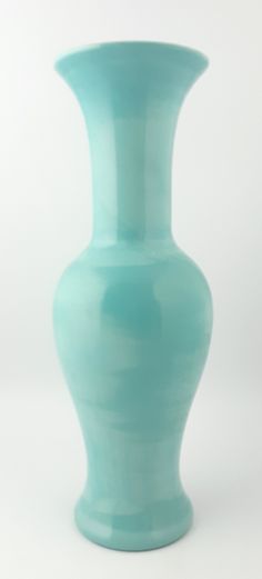 a light blue vase sitting on top of a white table