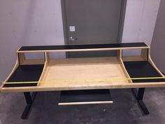 a wooden desk with black top and yellow tape on it