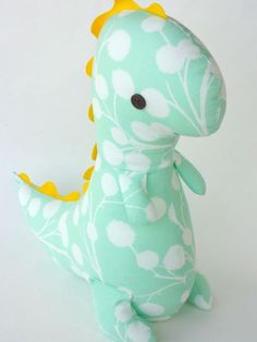 a stuffed toy dinosaur with white and yellow flowers on it's body, sitting in front of a white background