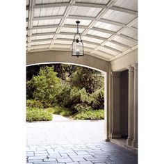 an open walkway with a light hanging from it's ceiling and trees in the background